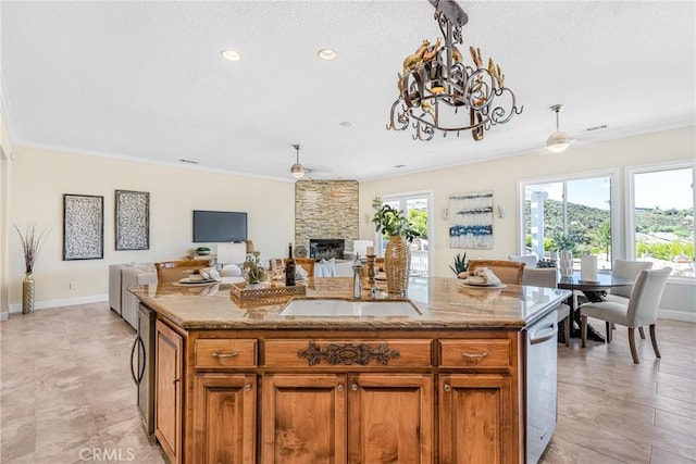 kitchen featuring sink, an island with sink, ceiling fan with notable chandelier, and ornamental molding