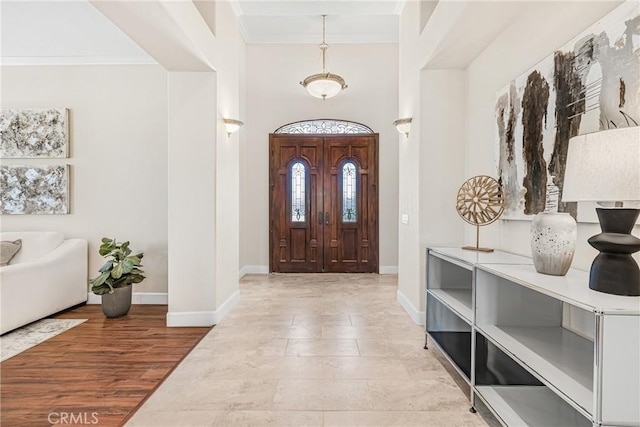 entrance foyer with wood-type flooring, ornamental molding, and a towering ceiling