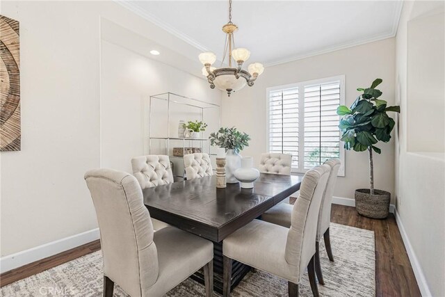 dining space featuring dark wood-type flooring, a notable chandelier, and ornamental molding