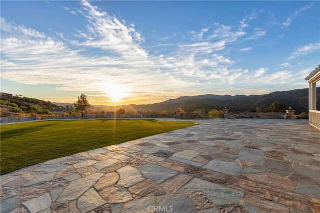 patio terrace at dusk with a mountain view and a yard