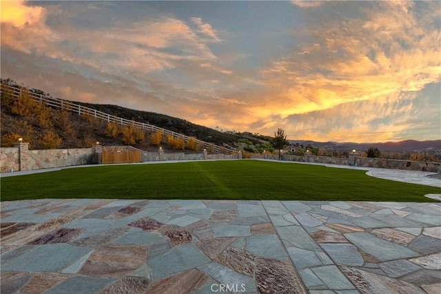 view of property's community featuring a mountain view, a yard, and a patio