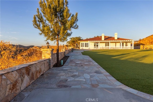 view of front facade featuring a patio area, a mountain view, and a front yard