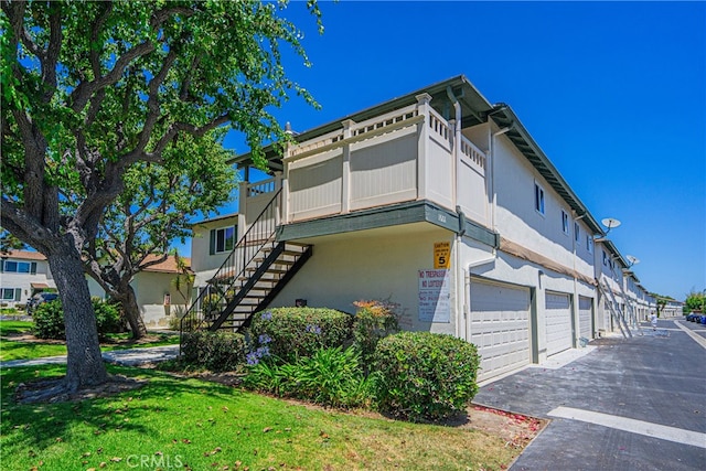 view of property exterior featuring a balcony, a garage, and a yard