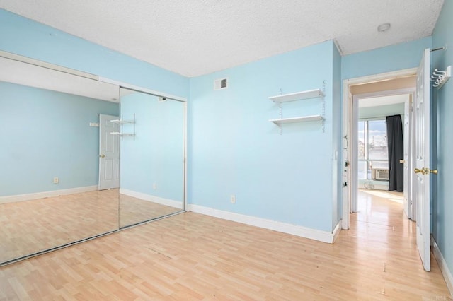 unfurnished bedroom with a textured ceiling, a closet, and light wood-type flooring