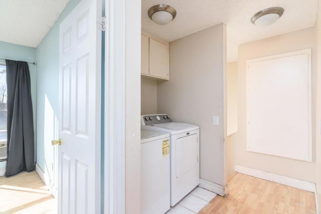 laundry room with light wood-type flooring, washing machine and dryer, and cabinets