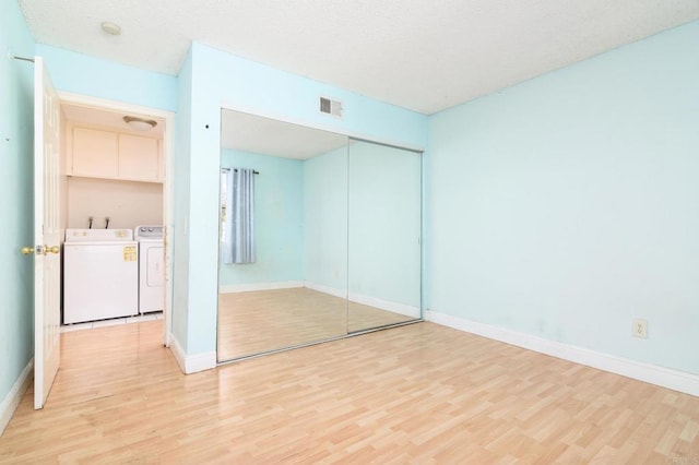 unfurnished bedroom with a closet, separate washer and dryer, and light hardwood / wood-style flooring