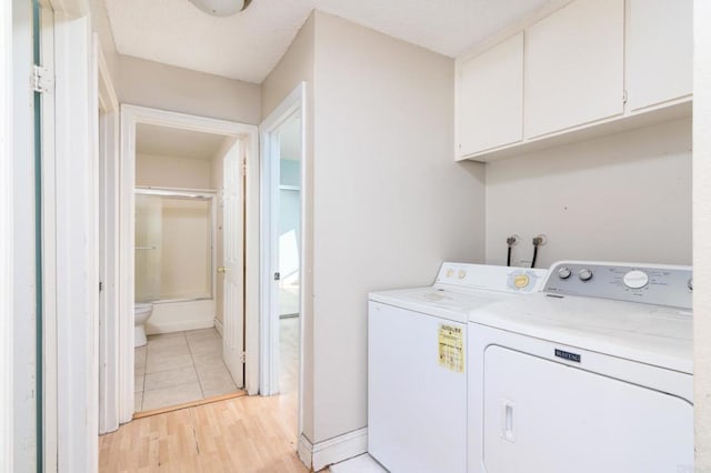 laundry area featuring cabinets, washer and clothes dryer, and light wood-type flooring