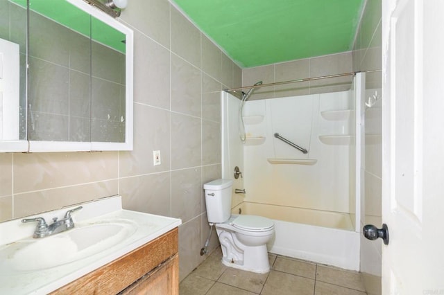 full bathroom featuring toilet, vanity, tile patterned flooring, tile walls, and shower / tub combination