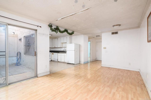 unfurnished living room featuring a textured ceiling, light hardwood / wood-style flooring, and sink