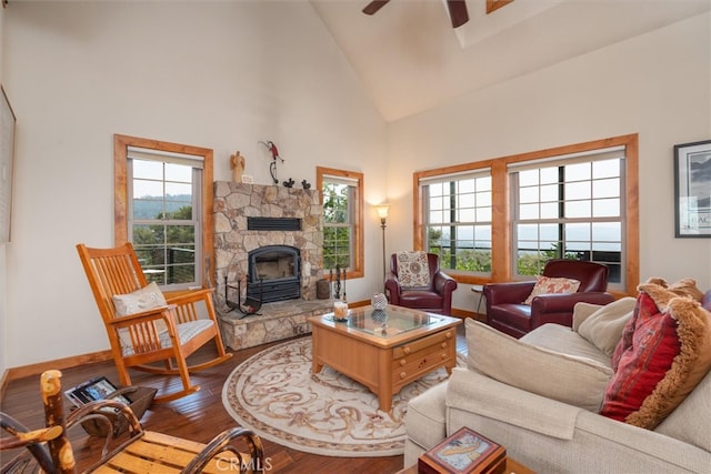 living room featuring wood-type flooring, a stone fireplace, high vaulted ceiling, and ceiling fan