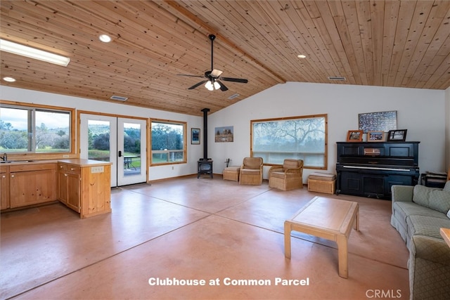 unfurnished living room with ceiling fan, lofted ceiling, a wood stove, concrete floors, and wooden ceiling