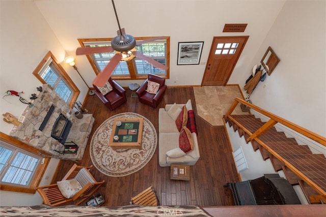 living room featuring a towering ceiling, ceiling fan, a fireplace, and dark hardwood / wood-style flooring