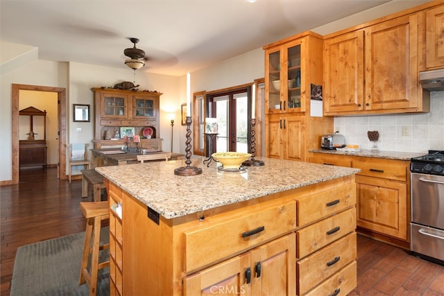 kitchen with dark wood-type flooring, stainless steel range oven, a kitchen island, and ventilation hood