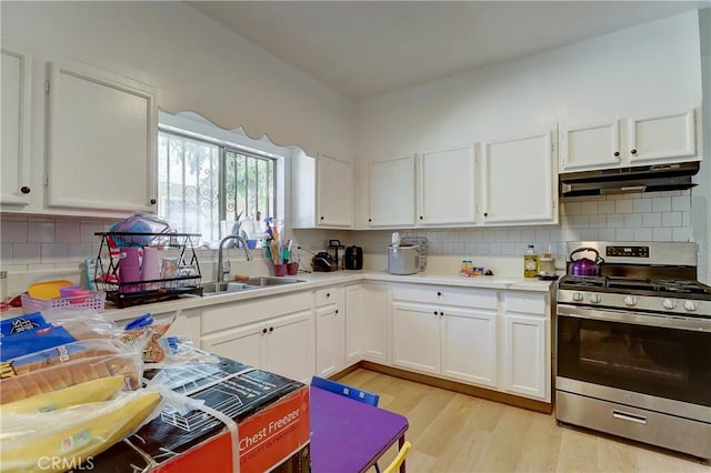 kitchen featuring decorative backsplash, light wood-type flooring, sink, stainless steel gas stove, and white cabinetry