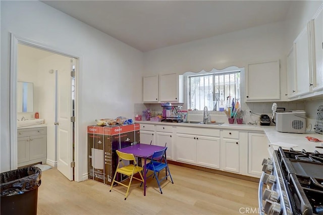 kitchen featuring light wood-type flooring, tasteful backsplash, white cabinetry, and sink