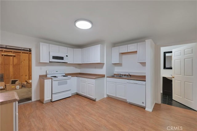 kitchen with white appliances, sink, light hardwood / wood-style floors, and white cabinets