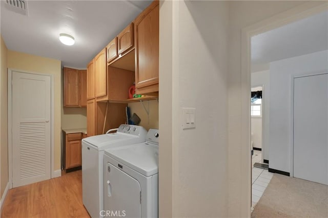 laundry room with cabinets, independent washer and dryer, and light hardwood / wood-style floors