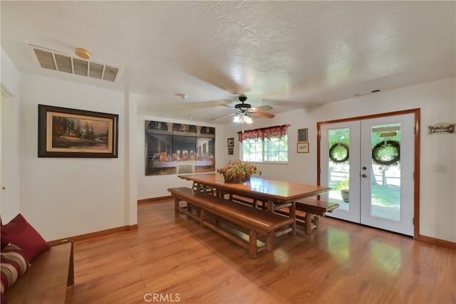 dining space featuring french doors, ceiling fan, a textured ceiling, and light hardwood / wood-style flooring