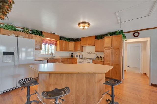 kitchen featuring sink, white appliances, light hardwood / wood-style flooring, a breakfast bar area, and a kitchen island