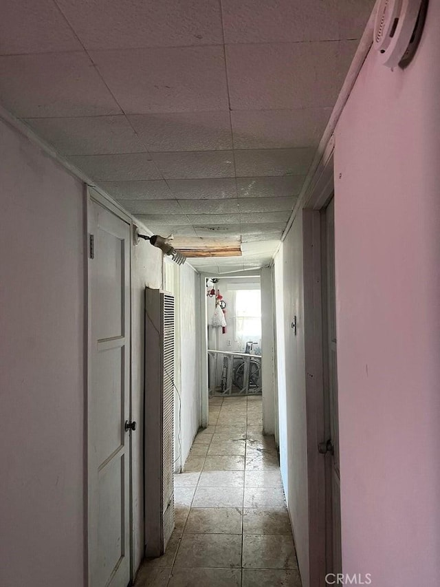 corridor featuring a heating unit and a drop ceiling