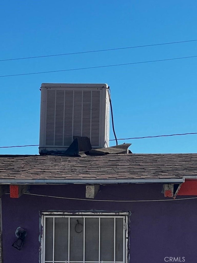 exterior details with central air condition unit, roof with shingles, and stucco siding