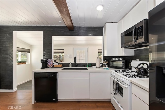 kitchen featuring sink, dark hardwood / wood-style floors, beam ceiling, white cabinetry, and stainless steel appliances