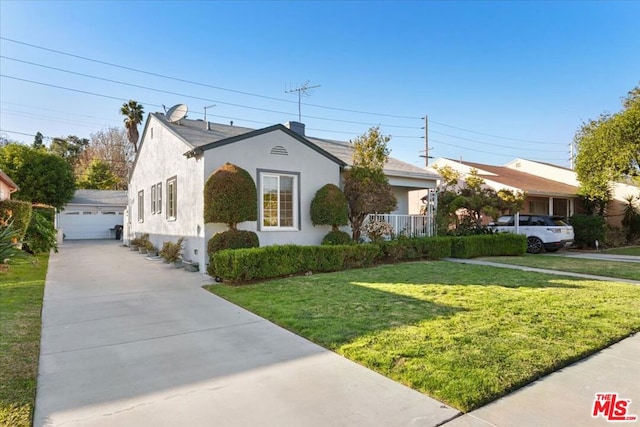 view of front of home featuring a front yard, a garage, and an outbuilding