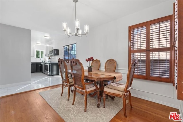 dining area featuring light wood-type flooring, sink, a chandelier, and a wealth of natural light