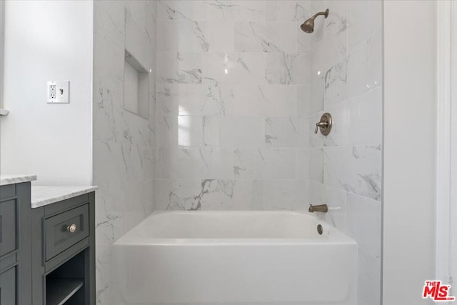 bathroom featuring tiled shower / bath combo and vanity