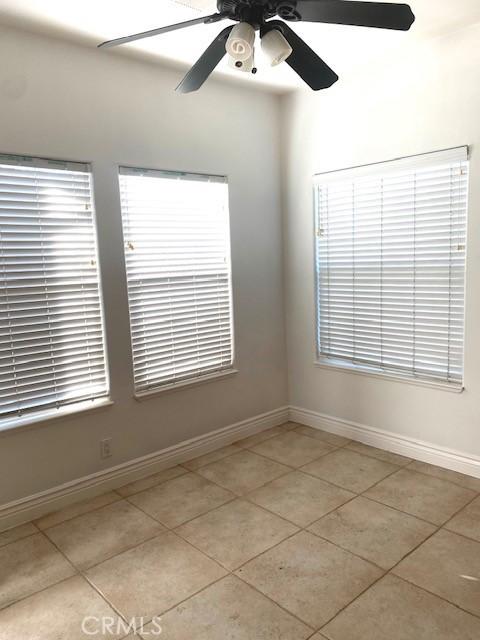 unfurnished room with baseboards, light tile patterned floors, and a ceiling fan