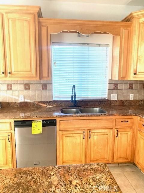 kitchen featuring light tile patterned flooring, a sink, dishwasher, and dark stone counters