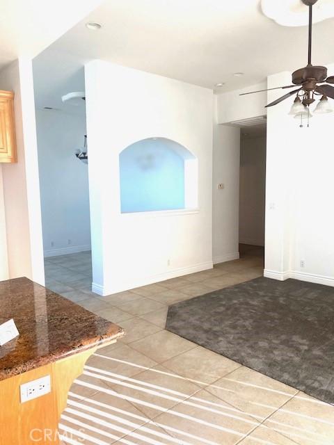 tiled spare room with baseboards and a ceiling fan