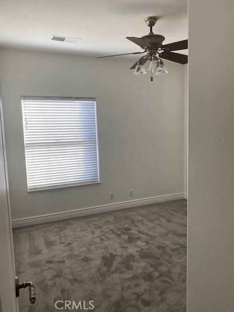 unfurnished room featuring carpet, baseboards, ceiling fan, and visible vents