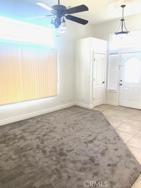 carpeted entrance foyer featuring tile patterned flooring, baseboards, and ceiling fan
