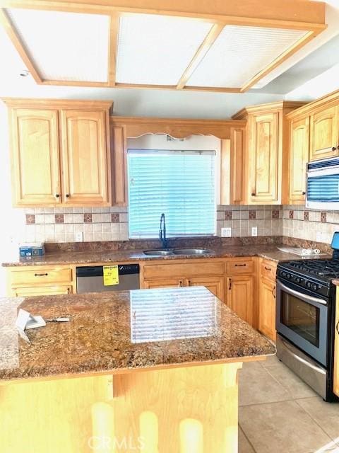 kitchen featuring light tile patterned floors, a sink, stainless steel appliances, and dark stone countertops