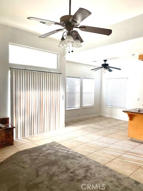 unfurnished living room featuring light tile patterned flooring, baseboards, and a ceiling fan