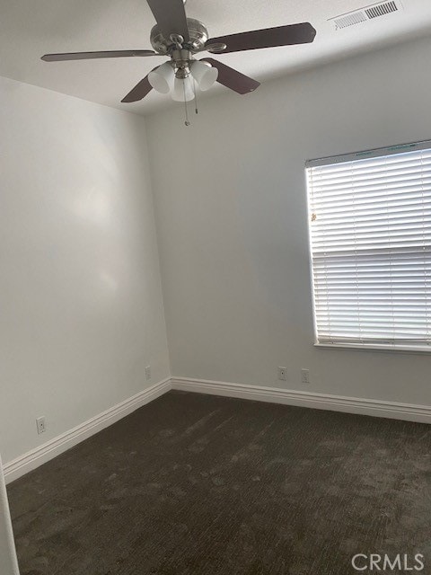 spare room with dark colored carpet and ceiling fan