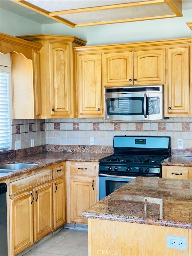 kitchen with dark stone countertops, stainless steel appliances, light tile patterned floors, and tasteful backsplash