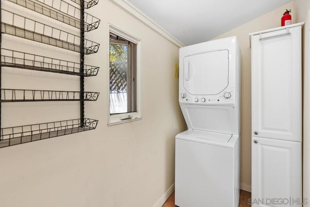 clothes washing area featuring stacked washer / dryer and crown molding