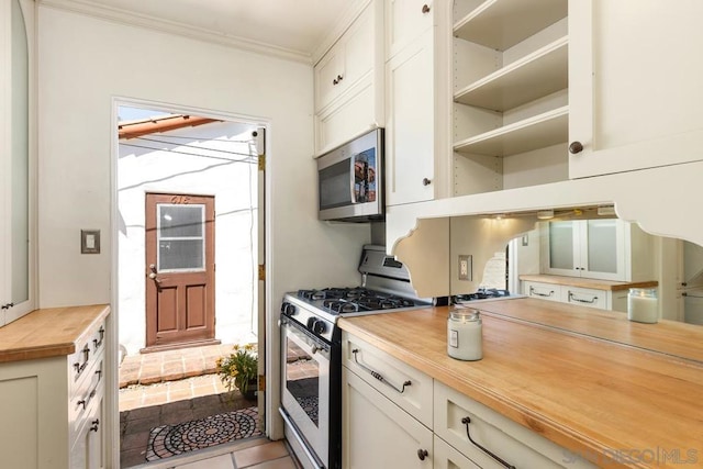 kitchen featuring light tile patterned floors, white cabinetry, white range with gas stovetop, crown molding, and wood counters