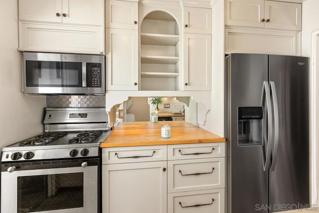 kitchen featuring stainless steel appliances, tasteful backsplash, and wooden counters