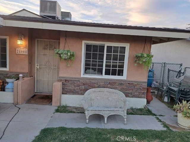 exterior entry at dusk with central AC unit and a patio area