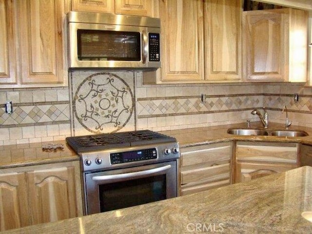 kitchen featuring light stone countertops, tasteful backsplash, stainless steel appliances, sink, and light brown cabinets