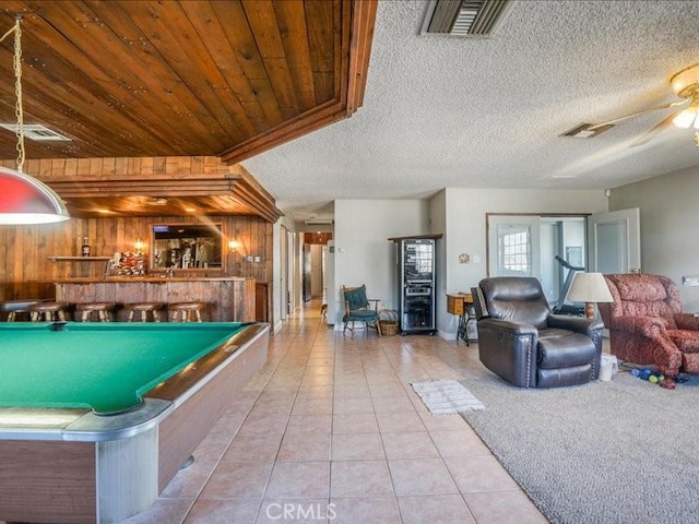 rec room with a textured ceiling, ceiling fan, wood walls, billiards, and light tile patterned flooring