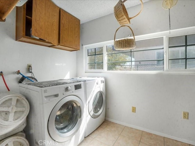 laundry room with cabinets, independent washer and dryer, a textured ceiling, and light tile patterned flooring