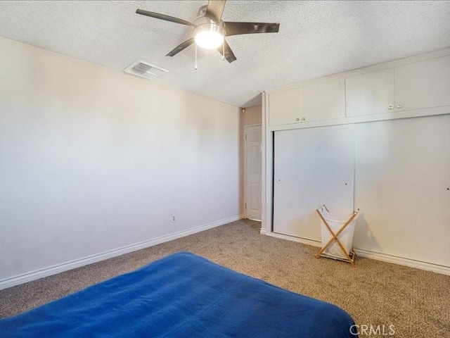 unfurnished bedroom with ceiling fan, a closet, carpet, and a textured ceiling