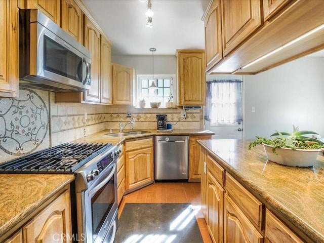 kitchen with sink, hanging light fixtures, stainless steel appliances, tasteful backsplash, and light stone counters