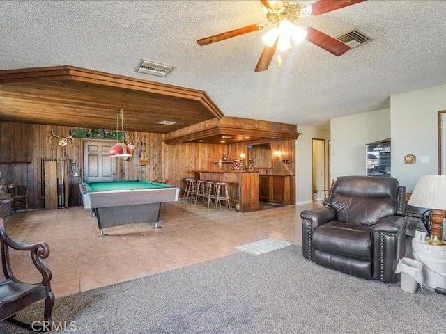 playroom with bar, wood walls, a textured ceiling, and billiards