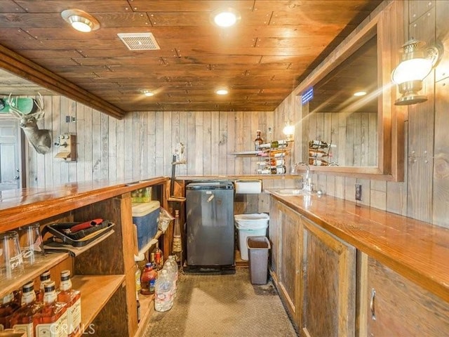 bar with dark carpet, sink, wooden ceiling, fridge, and wood walls