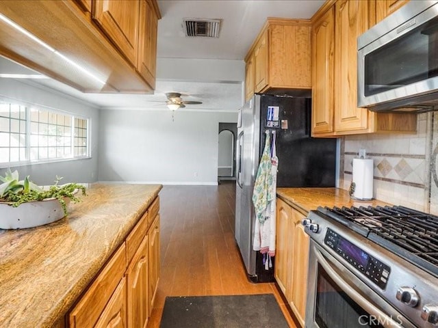 kitchen featuring ceiling fan, dark hardwood / wood-style flooring, stainless steel appliances, and tasteful backsplash